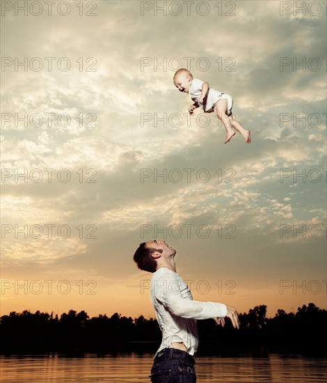 Father tossing baby son up in air. Photo : King Lawrence