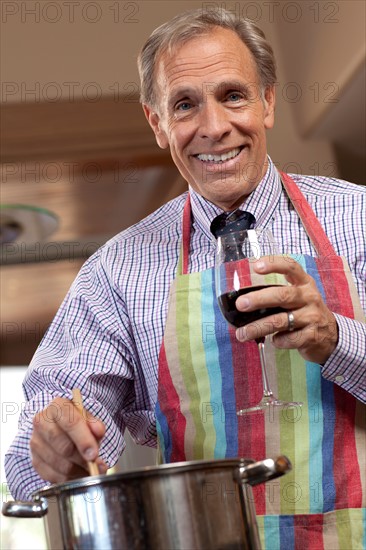 Portrait of man cooking and drinking wine. Photo : db2stock