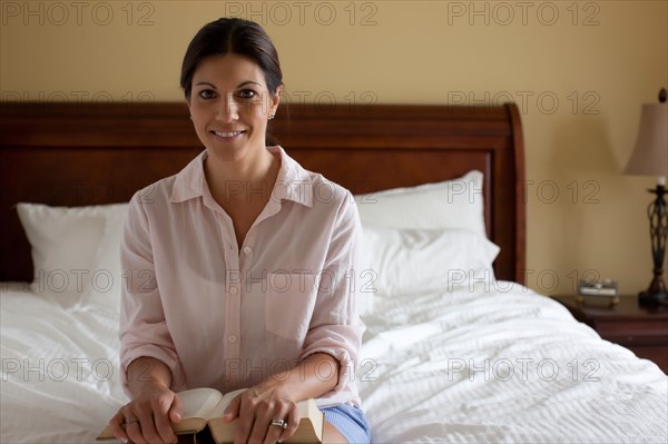 Portrait of woman reading on bed. Photo : db2stock