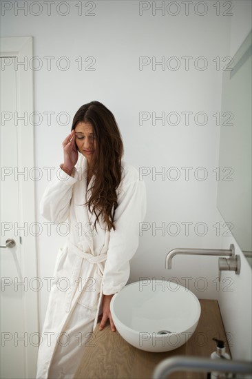 Young woman with headache in bathroom. Photo : Mark de Leeuw