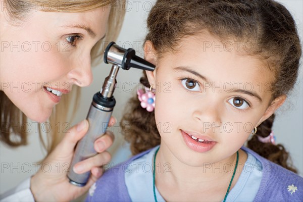 Doctor examining girl's (10-11) ear . Photo : Rob Lewine