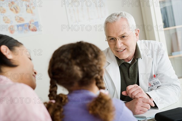 Girl (10-11) with mother talking to doctor. Photo : Rob Lewine