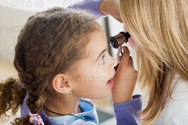 Girl (10-11) examining doctor's ear with otoscope. Photo : Rob Lewine