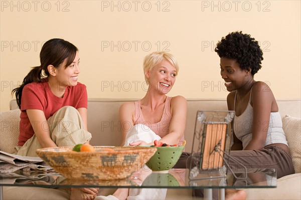 Three female friends sitting on sofa and talking. Photo : Rob Lewine