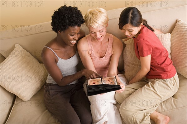 Three girlfriends looking at photo album. Photo : Rob Lewine