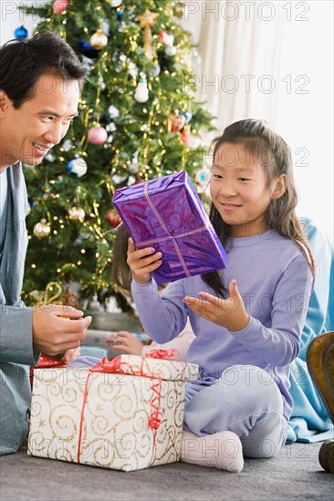 Father and daughter unwrapping christmas gifts. Photo : Rob Lewine