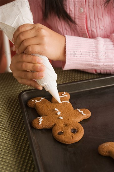 Teenage girl (16-17) decorating gingerbread with icing. Photo : Rob Lewine