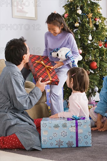 Father and daughters (10-11) unwrapping christmas gifts. Photo : Rob Lewine