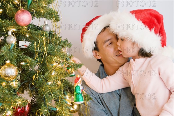 Father and daughter (10-11) decorating christmas tree. Photo : Rob Lewine