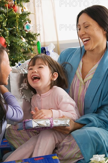 Mother and daughters (10-11) unwrapping christmas gifts. Photo : Rob Lewine
