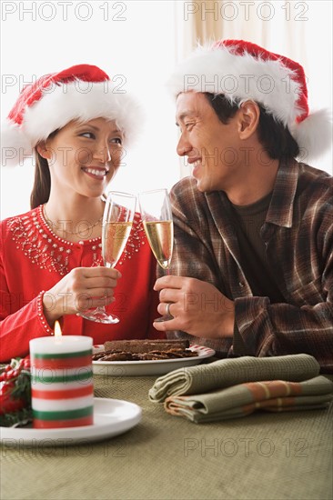 Couple wearing santa hats toasting with champagne. Photo : Rob Lewine