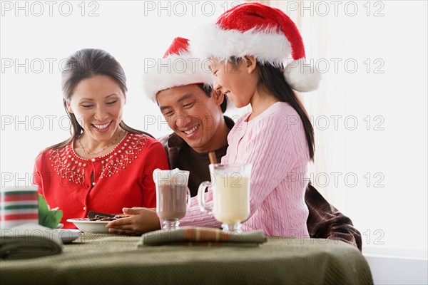 Girl (10-11) wearing Santa hat serving cookies to parents. Photo : Rob Lewine