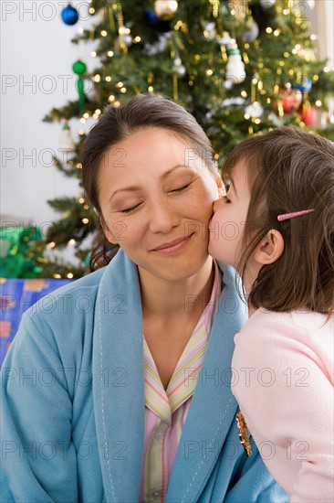 Girl kissing mother at Christmas morning. Photo : Rob Lewine