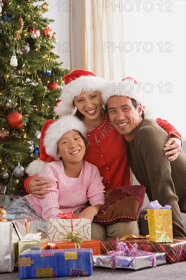 Portrait of parents with daughter (10-11) at Christmas tree. Photo : Rob Lewine