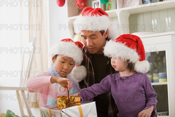 Father with two daughters (10-11) opening Christmas present. Photo : Rob Lewine