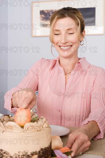Portrait of mature woman cutting cake. Photo : Rob Lewine