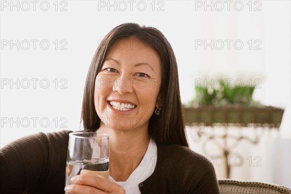 Portrait of smiling woman holding glass of water. Photo : Rob Lewine