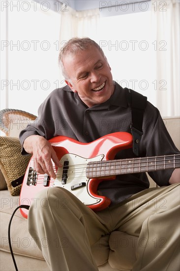 Man eagerly playing electric guitar. Photo : Rob Lewine