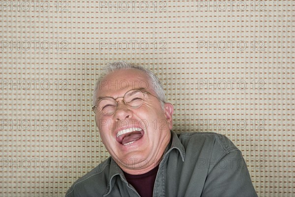 Studio portrait of senior man laughing. Photo : Rob Lewine
