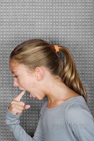 Studio portrait of girl (12-13) inserting finger in mouth. Photo : Rob Lewine