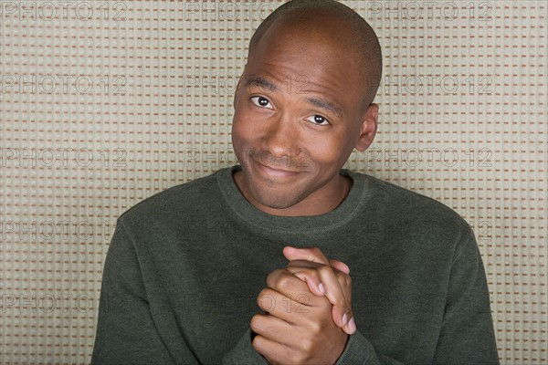 Studio portrait of mid adult man with hands clasped. Photo : Rob Lewine