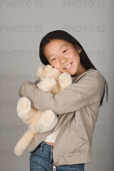 Studio portrait of teen (16-17) hugging stuffed toy. Photo : Rob Lewine