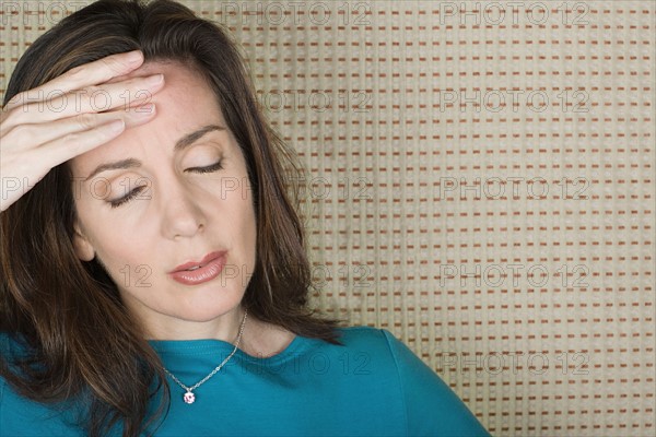 Studio portrait of mature woman with hand on forehead. Photo : Rob Lewine