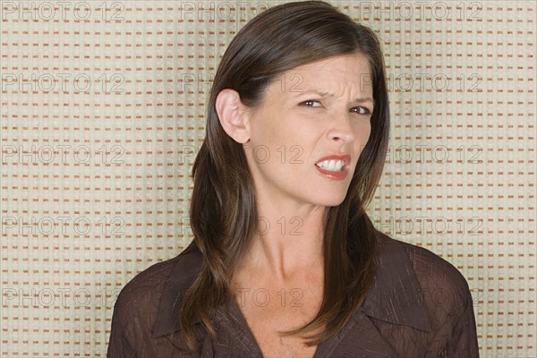 Studio portrait of mid adult woman grimacing. Photo : Rob Lewine