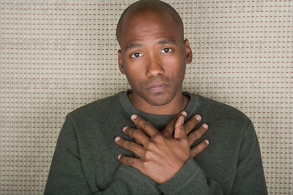 Studio portrait of mid adult man with hands folded on chest. Photo : Rob Lewine