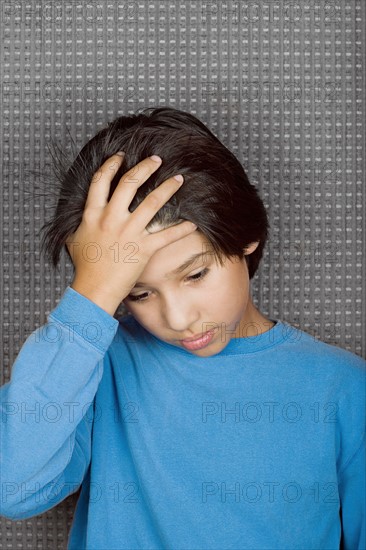 Studio portrait of boy with hand on forehead. Photo : Rob Lewine