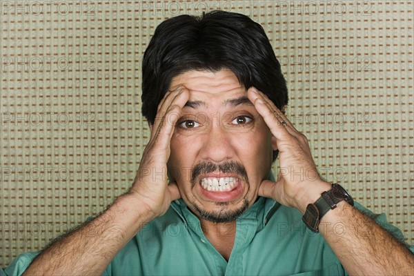 Studio portrait of mature man with head in hands. Photo : Rob Lewine