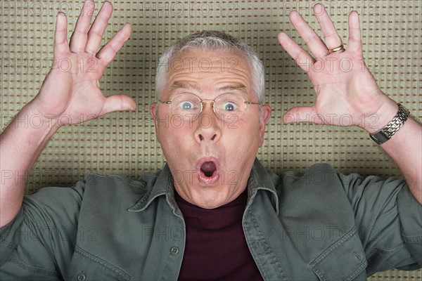 Studio portrait of senior man with arms raised. Photo : Rob Lewine