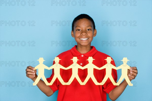 Studio portrait of teenage boy holding paper cutout. Photo : Rob Lewine