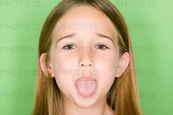 Studio portrait of teenage (16-17) girl sticking out tongue. Photo : Rob Lewine