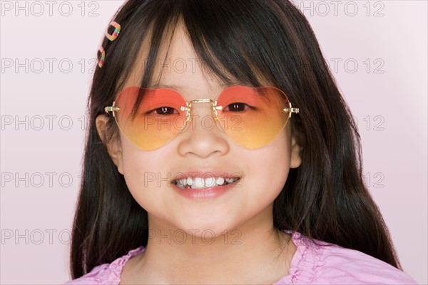 Studio portrait of girl wearing heart-shaped glasses. Photo : Rob Lewine