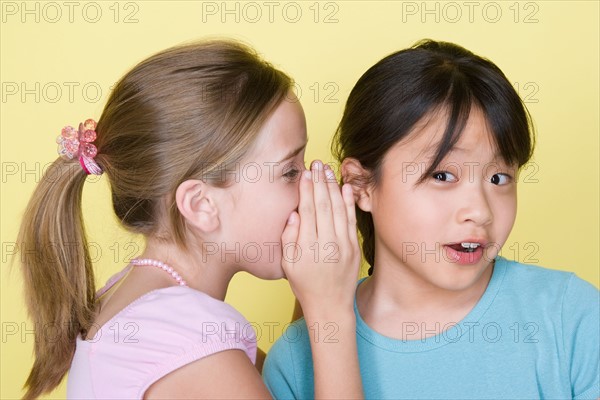 Studio portrait of teenage (16-17) girls gossiping. Photo : Rob Lewine