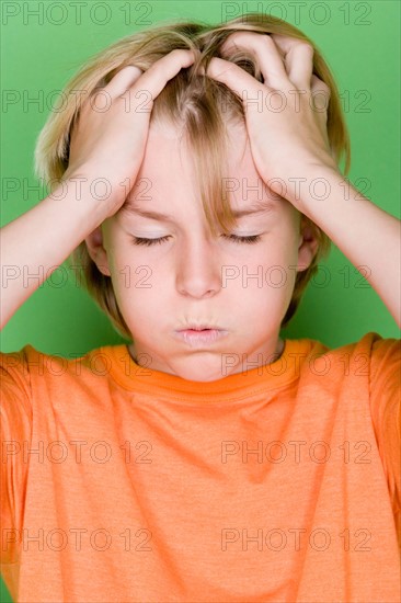 Studio portrait of teenage (16-17) boy with head in hands. Photo : Rob Lewine