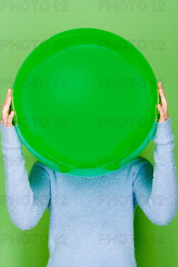 Studio shot portrait of teenage girl holding ball in front of her face, waist up. Photo : Rob Lewine