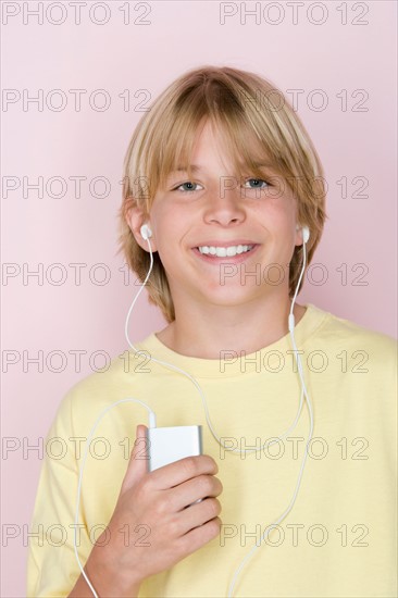 Studio shot portrait of teenage boy with mp3 player, head and shoulders. Photo : Rob Lewine