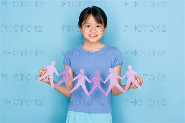 Studio shot portrait of teenage girl holding paper chain, waist up. Photo : Rob Lewine