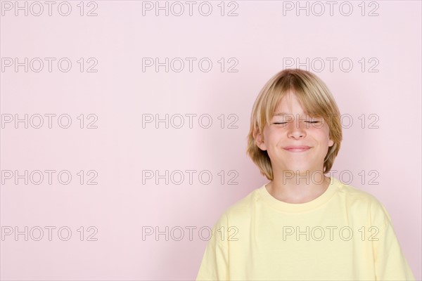 Studio shot portrait of teenage boy with eyes closed, head and shoulders. Photo : Rob Lewine
