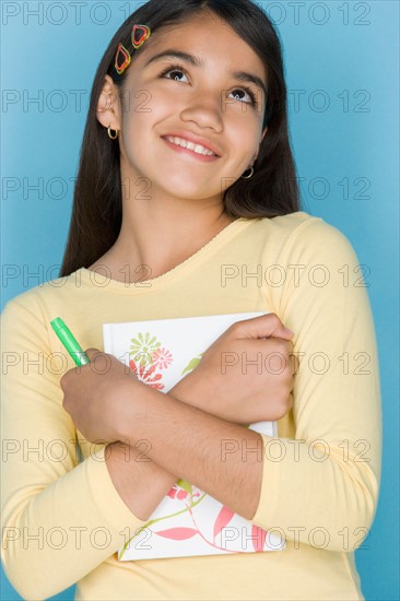 Studio shot portrait of teenage girl holding notebook, waist up. Photo : Rob Lewine