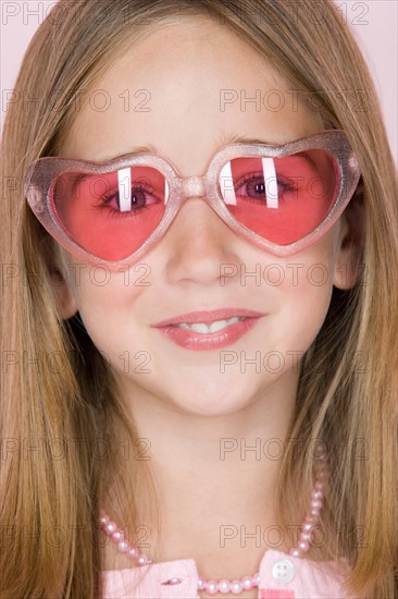 Studio shot portrait of teenage girl in pink sunglasses, close-up. Photo : Rob Lewine