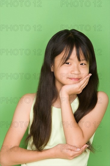 Studio shot portrait of teenage girl with hand on chin, waist up. Photo : Rob Lewine