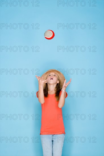 Studio shot portrait of teenage girl throwing ball, three quarter length. Photo : Rob Lewine