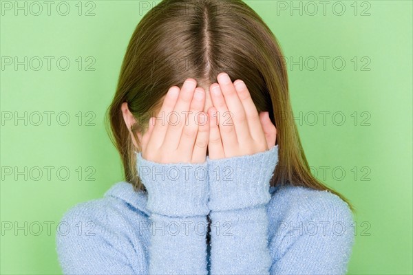 Studio shot portrait of teenage girl covering face, head and shoulders. Photo : Rob Lewine