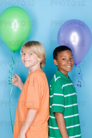 Studio shot portrait of two teenagers with balloons, waist up. Photo : Rob Lewine