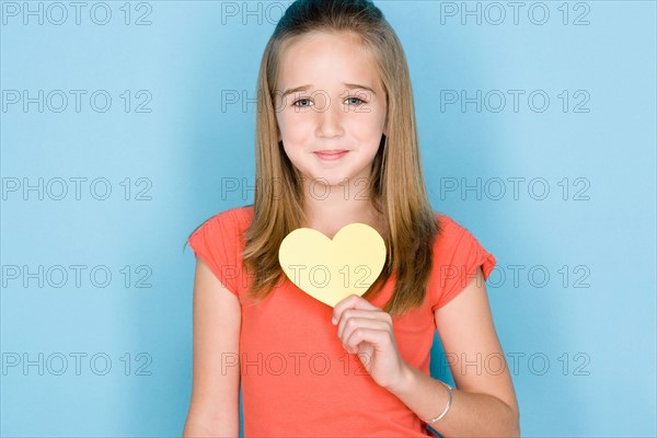 Studio shot portrait of teenage girl holding hart, head and shoulders. Photo : Rob Lewine
