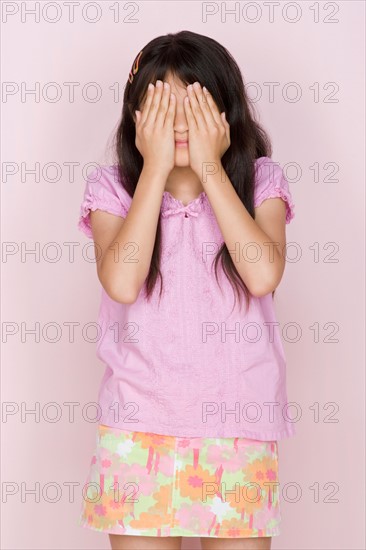 Studio shot portrait of teenage girl covering face, three quarter length. Photo : Rob Lewine