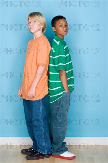 Studio shot portrait of two teenagers standing back to back, full length. Photo : Rob Lewine